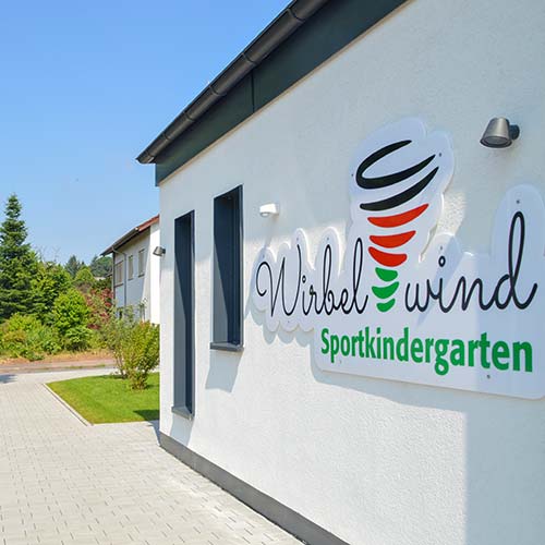 Ein Kind krabbelt durch einen Reifen im Sportkindergarten